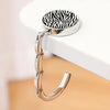 A silver zinc alloy folding handbag hook with a black and white zebra print top.