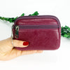 A hand holds a compact purple PU leather mini wallet with a silver keychain against a white background.