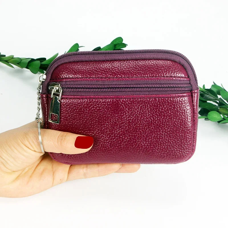 A hand holds a compact purple PU leather mini wallet with a silver keychain against a white background.