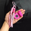 Pink D-shape nylon fitness keychain with a pink silicone fob and black cord attached to a hand.