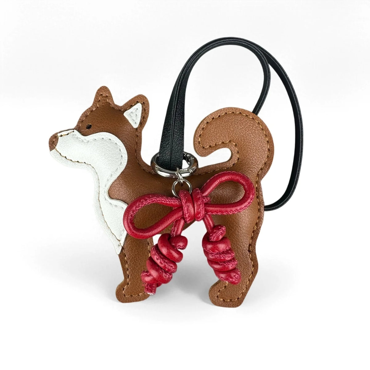 Colgante de perro Shiba Inu marrón de cuero con un lazo rojo trenzado a mano y una correa negra.