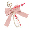 Llavero decorativo rosa con dije de corbata y collar de perlas.