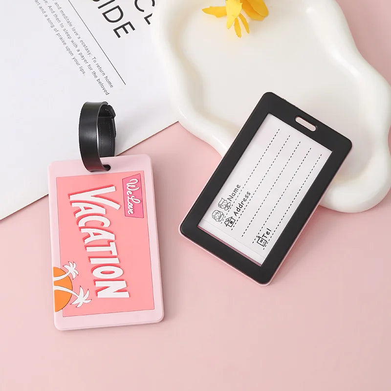 Pink silicone letter luggage tags with black straps resting on a white tray.