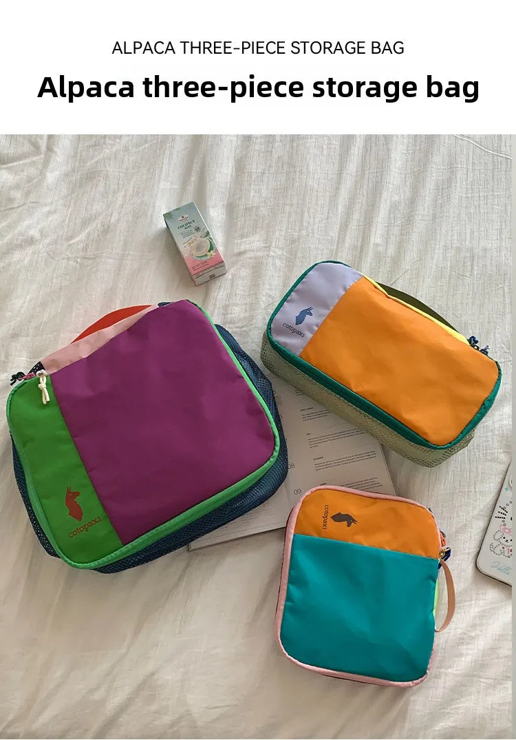 A purple and green alpaca three-piece storage bag set lying on a white surface.