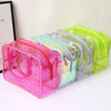 A set of clear waterproof makeup organizer bags in pink, blue, gray, and lime green.