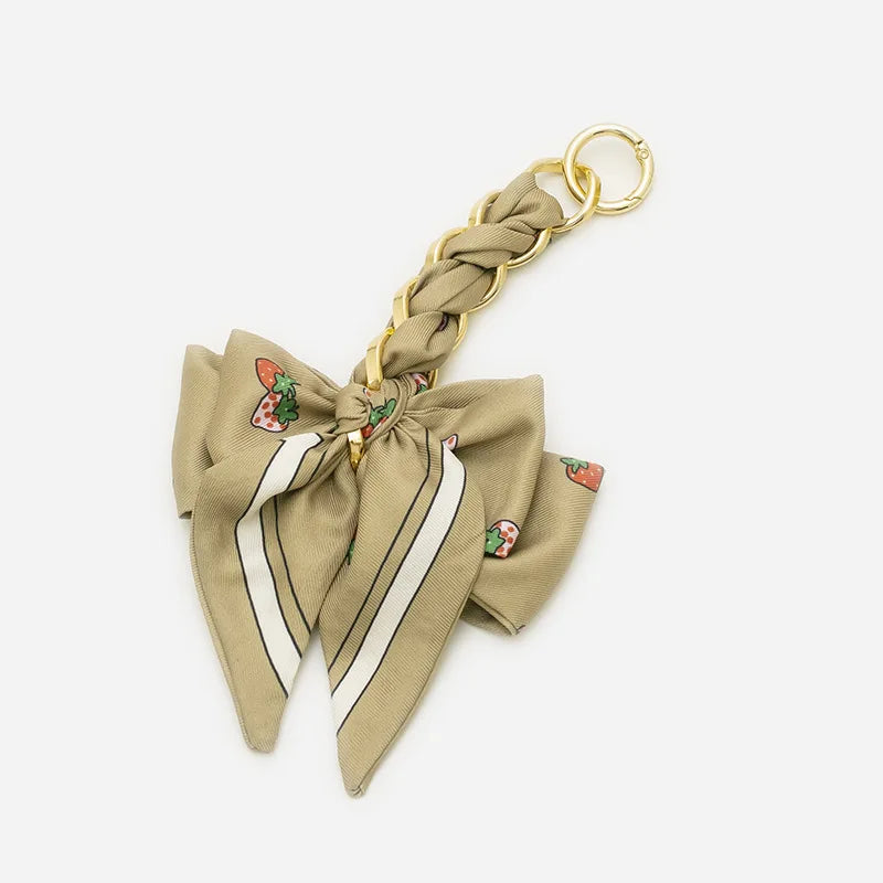 A beige braided adjustable bag strap with a gold-colored ring and decorative stitching.