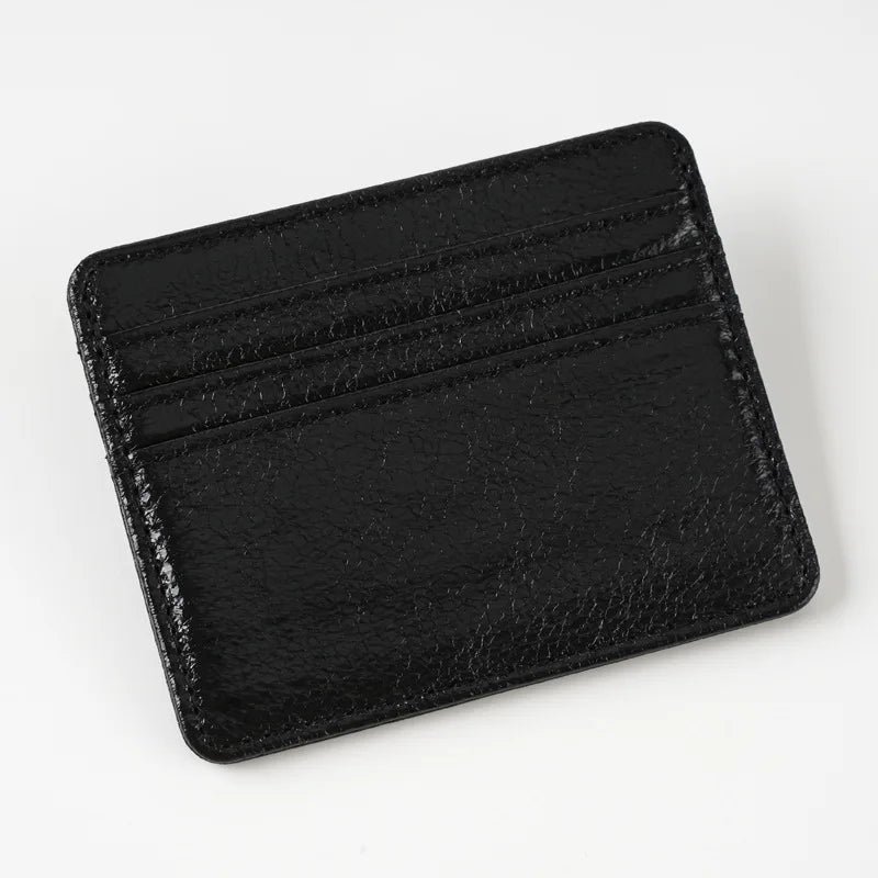 A black slim leather mini wallet card holder with embossed lines.