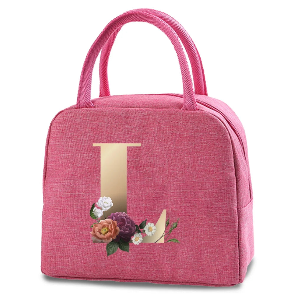 A pink insulated canvas lunch bag with a gold letter T print and pink straps.