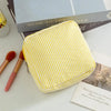 A yellow striped storage pouch is shown next to makeup brushes and a book.