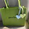 A lime green PU leather tote bag with a light blue and pale green heart keychain attached.