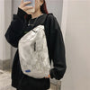 Eine Person hält eine weiße karierte Tasche vor einem hellen Hintergrund.