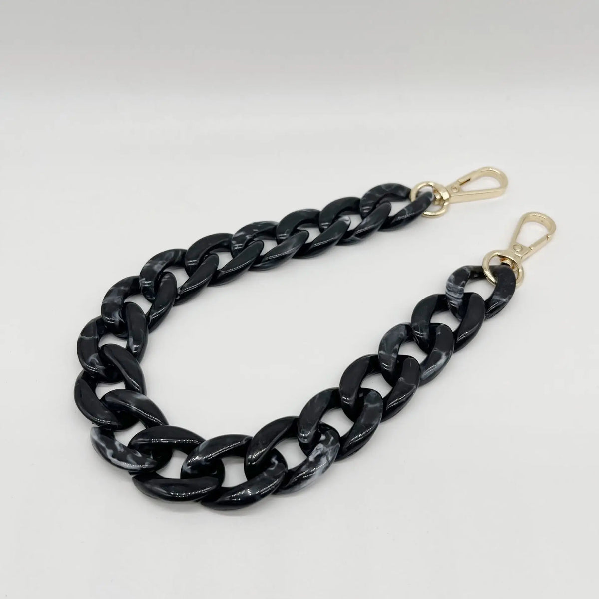 A black acrylic chain bracelet with gold-colored clasps.
