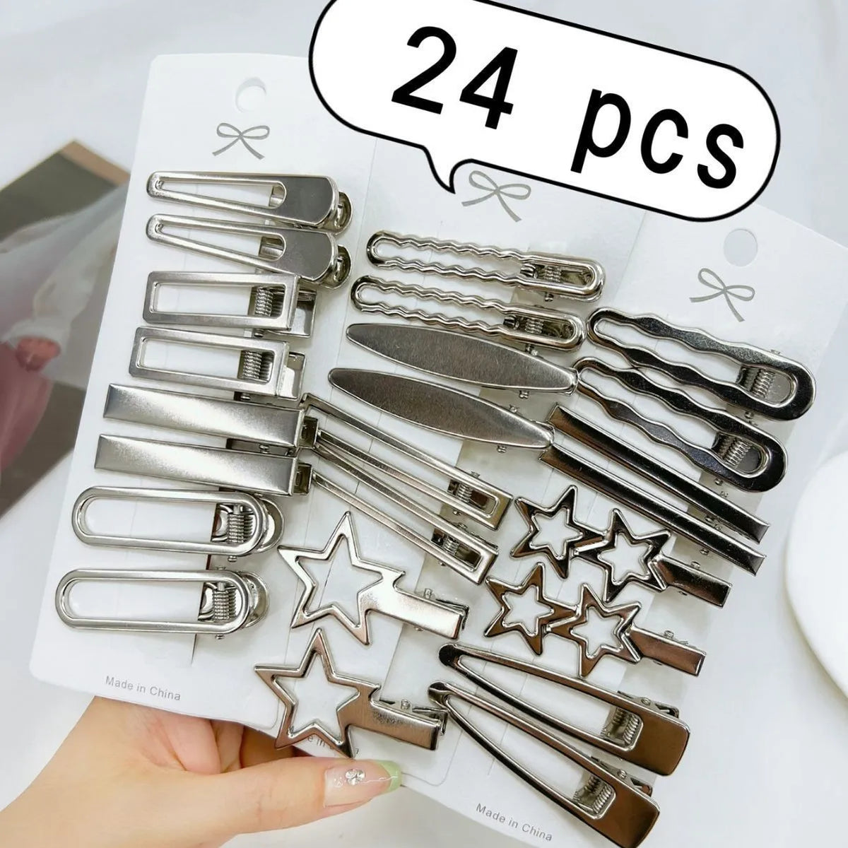 A collection of 24 silver metal star hairpins and clips are displayed on a white background.