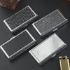 Three metal cigarette case holders with different textures and designs are displayed on a dark surface.