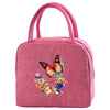 A pink insulated canvas lunch bag with pink fabric handles and a floral butterfly design.
