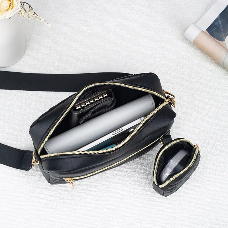 Schwarze gesteppte Crossbody-Tasche mit goldfarbenem Riemchen und Innenfutter auf weißem Untergrund.