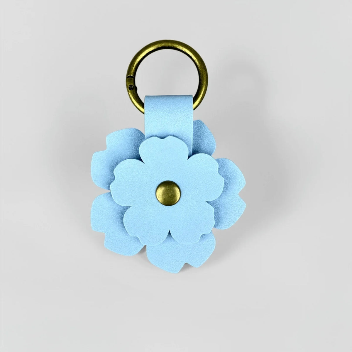 A light blue floral PU leather keychain with a gold-toned ring and a matching fabric charm.