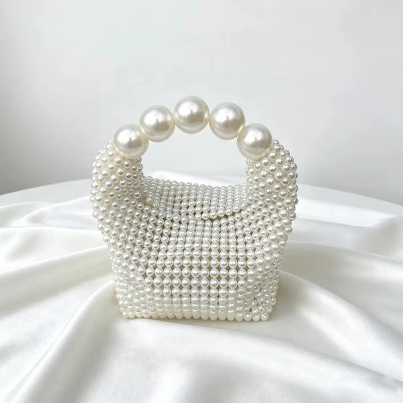 A white beaded clutch bag featuring pearl embellishments and a pearl-encrusted handle.