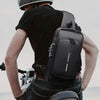 Eine Person in schwarzem Shirt und Jeans fährt Fahrrad und trägt eine schwarze Designer-Crossbody-Tasche.