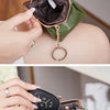 A close-up display of a green leather coin purse with a gold chain and ring clasp.