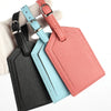Three pink, blue, and black PU leather luggage tags with silver hardware stacked on a light background.