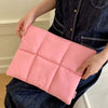 A pink quilted laptop sleeve is being held by a person wearing a dark denim shirt.