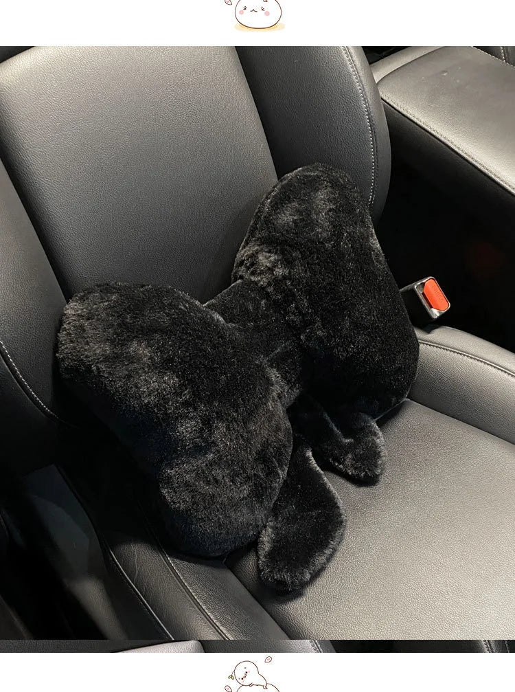 A black, fuzzy bowknot car headrest pillow and lumbar support placed in a gray car seat.
