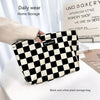 A black and white plaid storage bag is shown being held by a hand on a white surface.