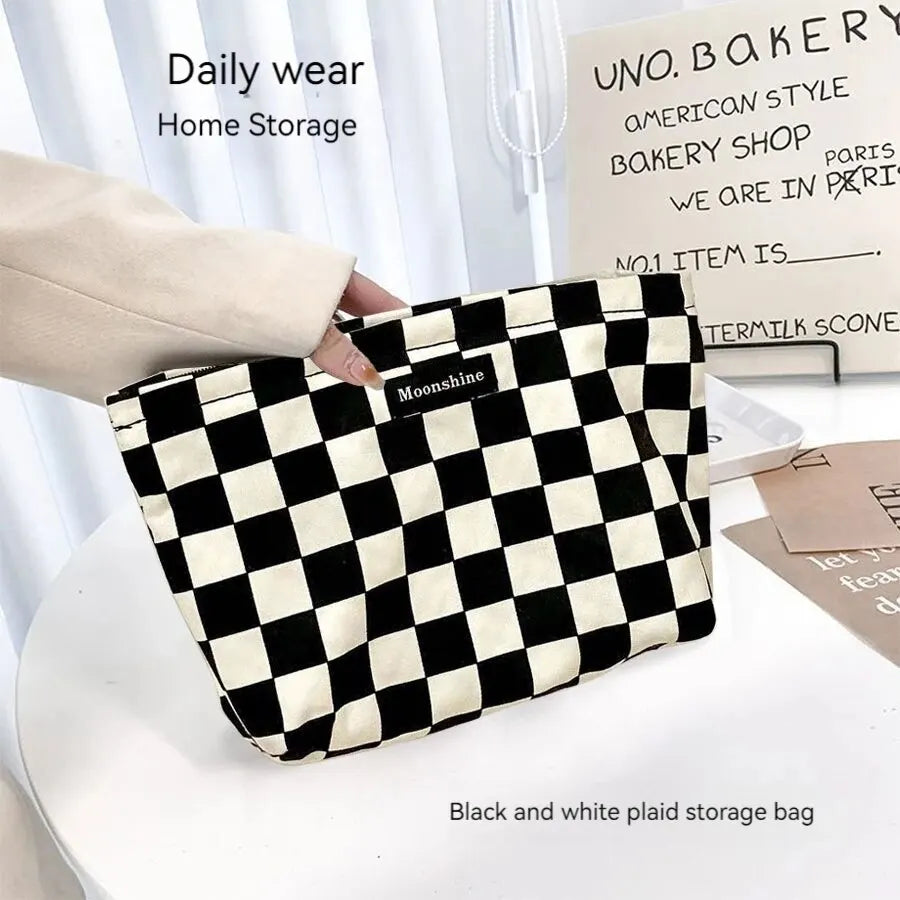 A black and white plaid storage bag is shown being held by a hand on a white surface.