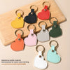 A collection of assorted color leather heart keychains arranged on a wooden board.