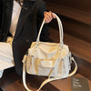 Bolso cruz de cuero suave blanco de lujo sostenido por una mujer con blazer negro.