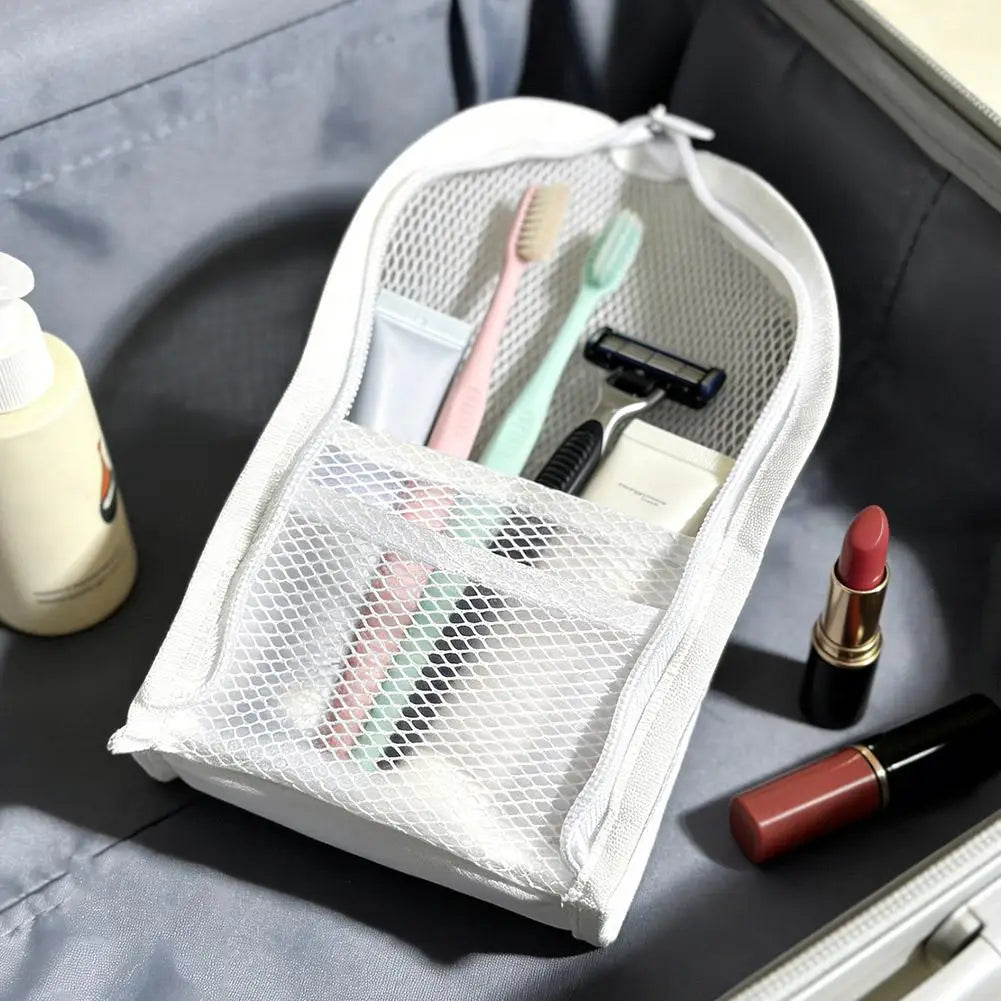 Una bolsa de cosméticos de malla blanca llena de pinceles y herramientas, dentro de una caja de almacenamiento gris.