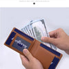 A hand holds an open brown leather wallet with a money clip and cash, demonstrating physical shooting.