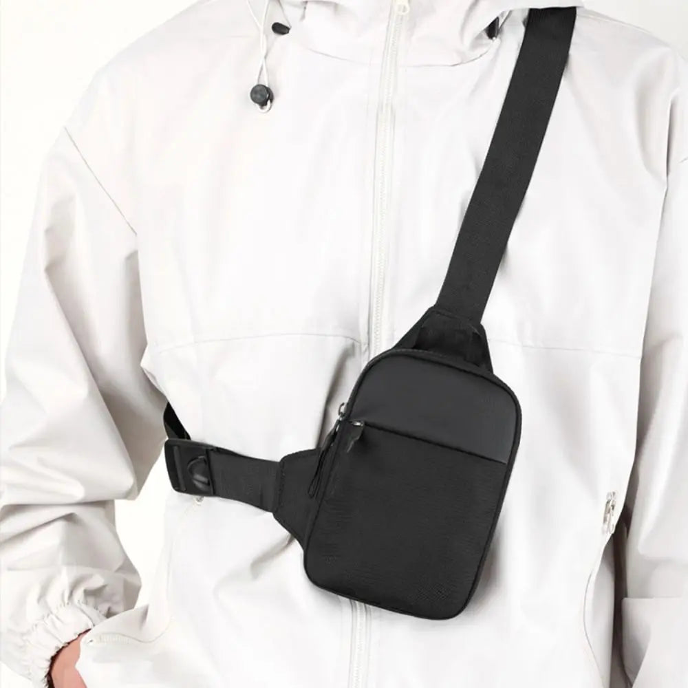 A black canvas crossbody sling bag is attached to the front of a white jacket.