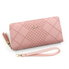 A pink quilted clutch wallet with gold hardware and a matching leather strap.