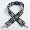 A black and white floral jacquard strap for a crossbody bag, featuring an adjustable buckle.