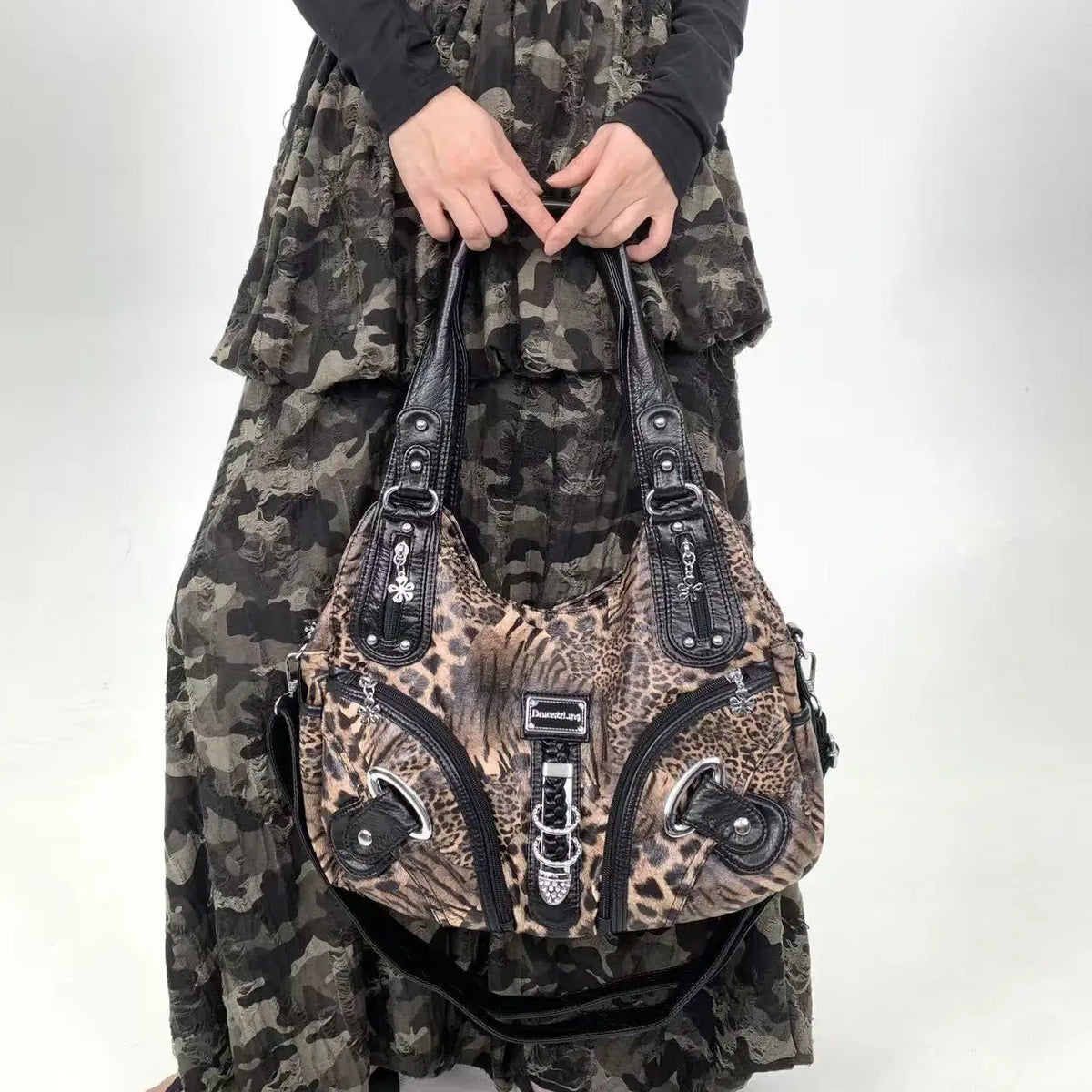 A leopard print crossbody shoulder bag with multiple compartments worn by a person in camouflage clothing.