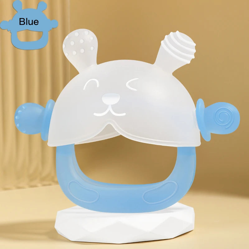 A white and blue silicone teether shaped like a bunny for hand sucking, displayed on a stand.