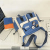 Bolso cruz de nylon azul y beige con correas negras sobre un escritorio blanco junto a una computadora portátil.