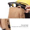 A close-up of a tan soft corduroy diaper backpack with black straps being attached to a stroller.