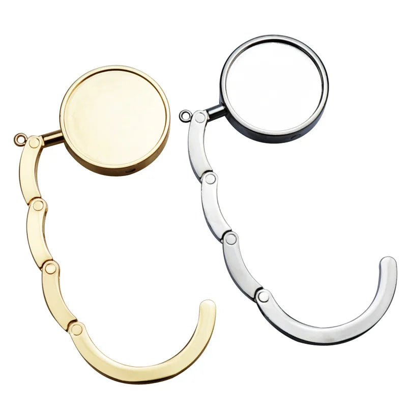 A pair of folding alloy handbag hangers with circular hooks and curved arms.