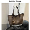 A brown faux leather tote bag with a monogram print is displayed against a light wall.