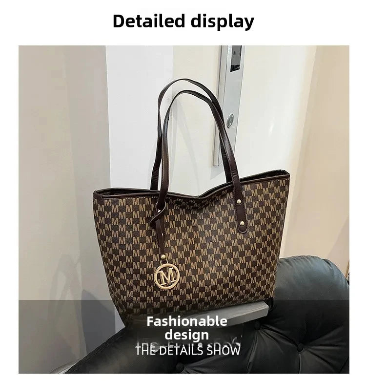 A brown faux leather tote bag with a monogram print is displayed against a light wall.
