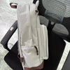A light beige canvas backpack with brown accents resting on a black office chair.
