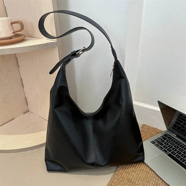 A black soft PU leather retro tote bag with a zipper closure resting on a light-colored surface.