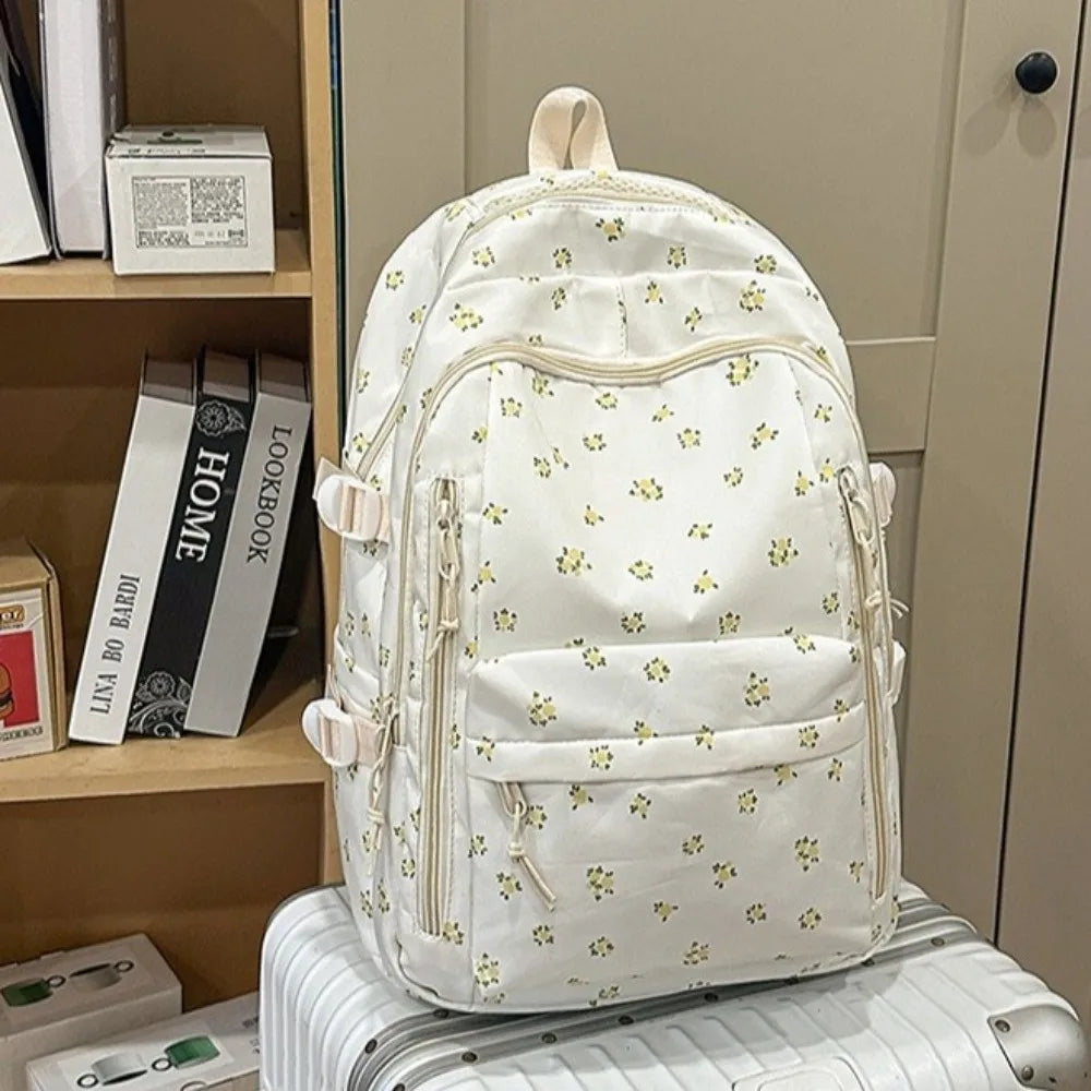 Mochila de varios bolsillos con estampado floral color crema sobre una superficie a rayas.