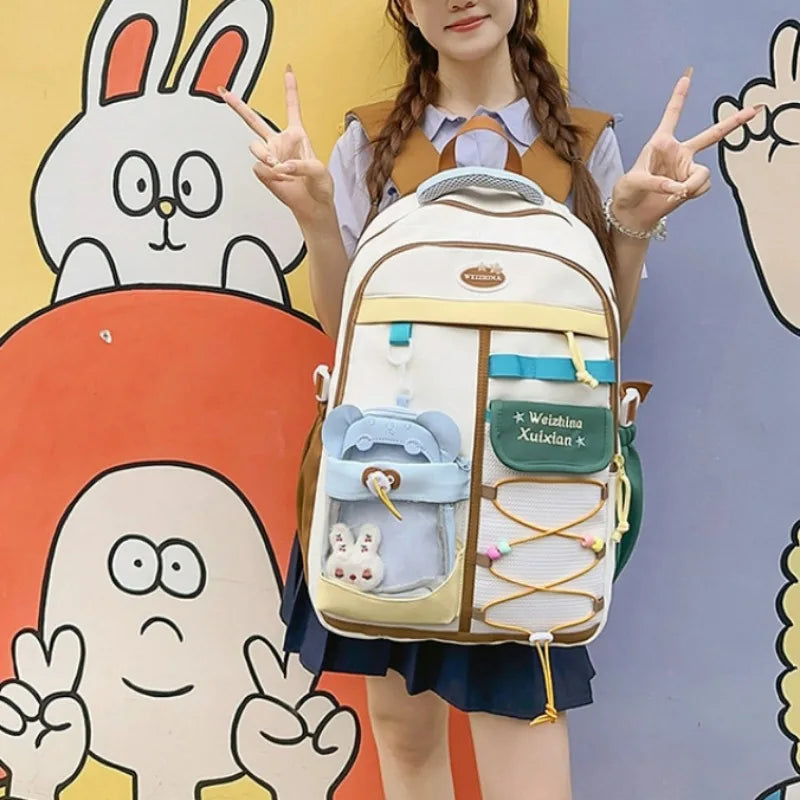 A woman is holding a beige and white Candy Color Campus backpack in front of colorful cartoon illustrations.