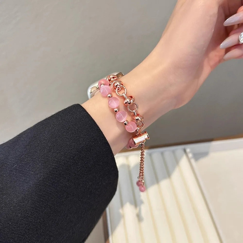 Nahaufnahme einer Hand mit einem rosa Kristallperlen-Metallgliedarmband am Handgelenk, kombiniert mit einem schwarzen Ärmel.