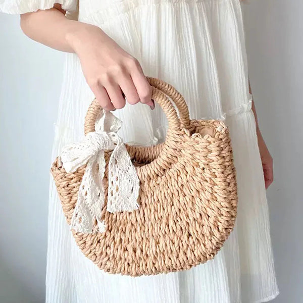 Un sac de plage en rotin tissé à la main tenu par une personne vêtue d'une robe blanche.