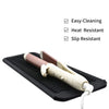 A black silicone mat with ridges holds a pair of styling tools, featuring easy-cleaning, heat resistant, and slip resistant p
